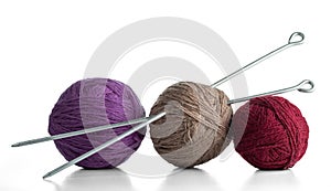 Three balls of yarn in different colors with knitting needles.