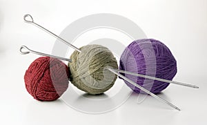 Three balls of yarn in different colors with knitting needles