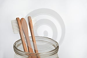 bamboo tooth brushes in a glass jar on a white background, copy space