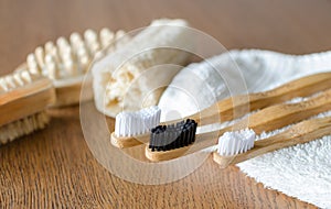 Three Bamboo toothbrushes with towel and eco natural plastic free luffa, wooden brushes on the background