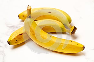 Three bananas on a white and gray marble kitchen counter