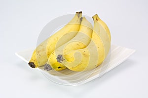 Three of bananas on white plate