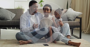 Three barefoot people couple with baby afro american family mother father and cute little girl daughter sitting at home