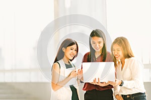 Three beautiful Asian girls on casual business meeting with laptop notebook and digital tablet at sunset