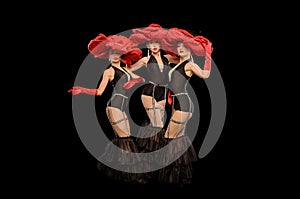 Three beautiful cabaret dancers in red hats isolated on black