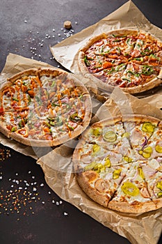 three beautiful colorful juicy different pizzas lie on parchment