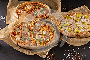 three beautiful colorful juicy different pizzas lie on parchment