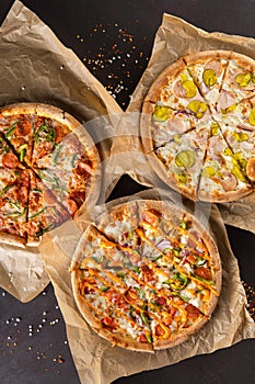 three beautiful colorful juicy different pizzas lie on parchment