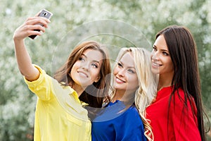 Three beautiful female friends being modern by taking selfies