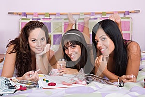 Three beautiful girls enjoying together on the bed