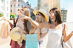 Beautiful girls in sunglasses with shopping bags in city