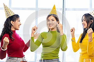 Three beautiful girls wearing party hats are having fun celebrating their birthday