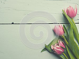 Three pink tulips on wood