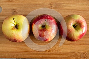 three beautiful red-yellow apples lying on a wooden background