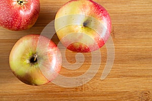 three beautiful red-yellow apples lying on a wooden triangle background