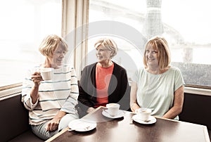 Three beautiful senior women enjoying retirement together having tea or coffee