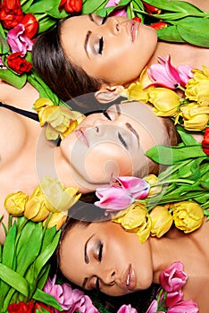 Three beautiful sensual women with colorful tulips