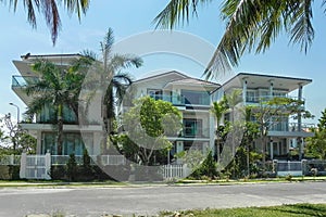 Three beautiful three-story houses with palm trees, trees, in the summer