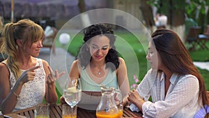 Three beautiful women having fun choosing meal, looking at the menu, laughing and gesturing