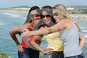 Three beautiful women taking selfie on the beach