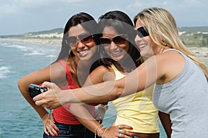 Three beautiful women taking selfie on the beach