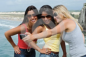 Three beautiful women taking selfie on the beach