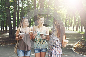 Three beautiful young boho chic stylish girls walking in park.