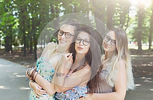 Three beautiful young boho chic stylish girls walking in park.