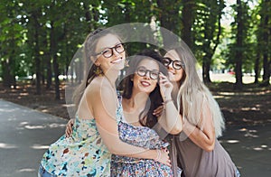 Three beautiful young boho chic stylish girls walking in park.