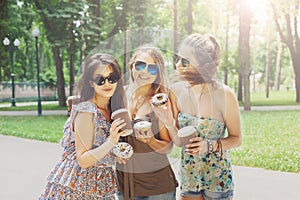 Three beautiful young boho chic stylish girls walking in park.