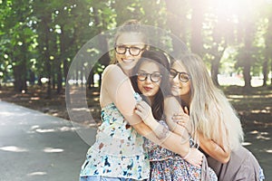 Three beautiful young boho chic stylish girls walking in park.