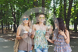 Three beautiful young boho chic stylish girls walking in park.