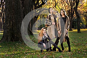 Three beautiful young models in autumn elegant clothes posing at Central Park.