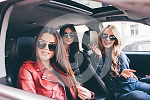 Three beautiful young women friends have fun in the o car as they go on a road trip