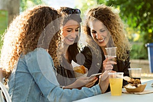 Three beautiful young women using they mobile phone in the street.