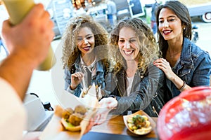 Three beautiful young women visiting eat market in the street.