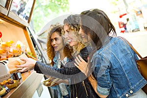 Three beautiful young women visiting eat market in the street.