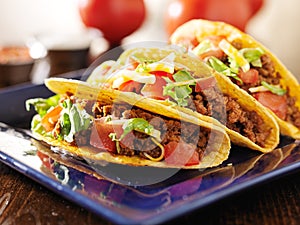 Three beef tacos with cheese, lettuce and tomatoes photo