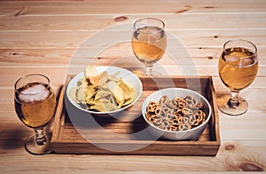 Three beer glasses and beer snacks on wooden table. Vintage styl