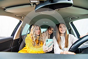 Three best friends in the car and riding ridiculous message. Woman showing her friends messages