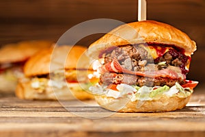 Three big burger with meat cooked on BBQ coal. Lunch on a wooden background. The concept of fast food and unhealthy food