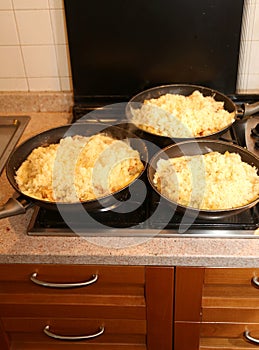 Three big pans with the food named frico a typical italian dish