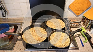 Three big pans with the food named frico a typical italian recip