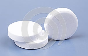 Three white medical pills on blue