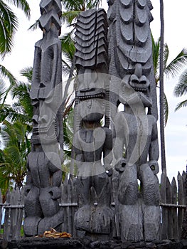 Three big wooden Tiki sculptures in the Pu`uhonua o Honaunau National Park, Big Island, Hawaii