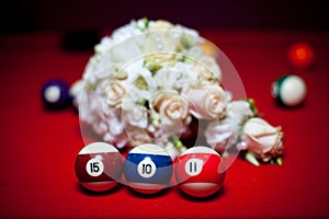 Three billiard balls stand in a row on a red table.
