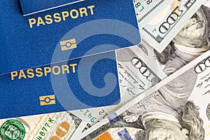 Three biometrical international passports over money background. Blue travel documents lying on US one hundred dollar banknotes. F