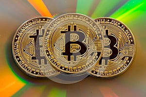 Three bitcoin tokens on colorful surface