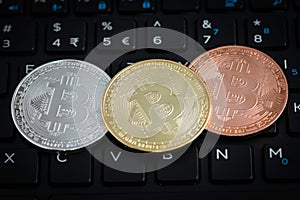 Three bitcoins on black keyboard