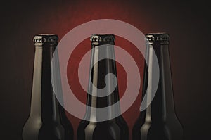 Three black bottle of beer on a dark background with red light/Three black bottle of beer on a dark background with red light. Se